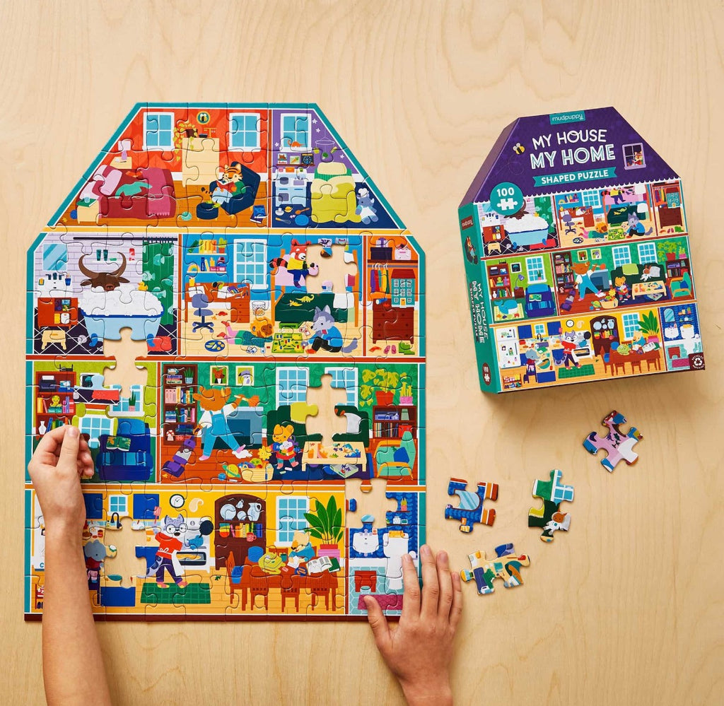 hands shown placing a piece on house shaped puzzle with box for puzzle in view